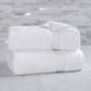 Two white towels stacked on a marble surface with a marble wall background