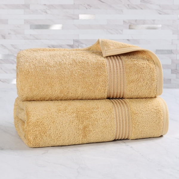Two folded beige towels on a light gray surface with a marble-patterned wall in the background.