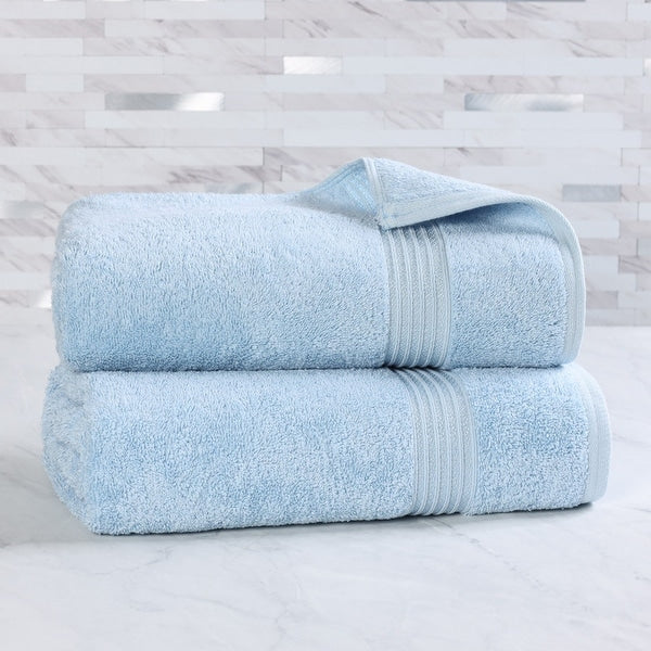 Two light blue towels stacked on a white surface with a light gray patterned wall in the background.
