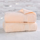 Two beige towels stacked on a marble surface with a tiled wall background
