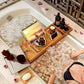 Person relaxing in a bathtub with a wooden tray, tablet, and snacks.