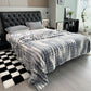 Gray checkered blanket draped over a bed in a bedroom setting.