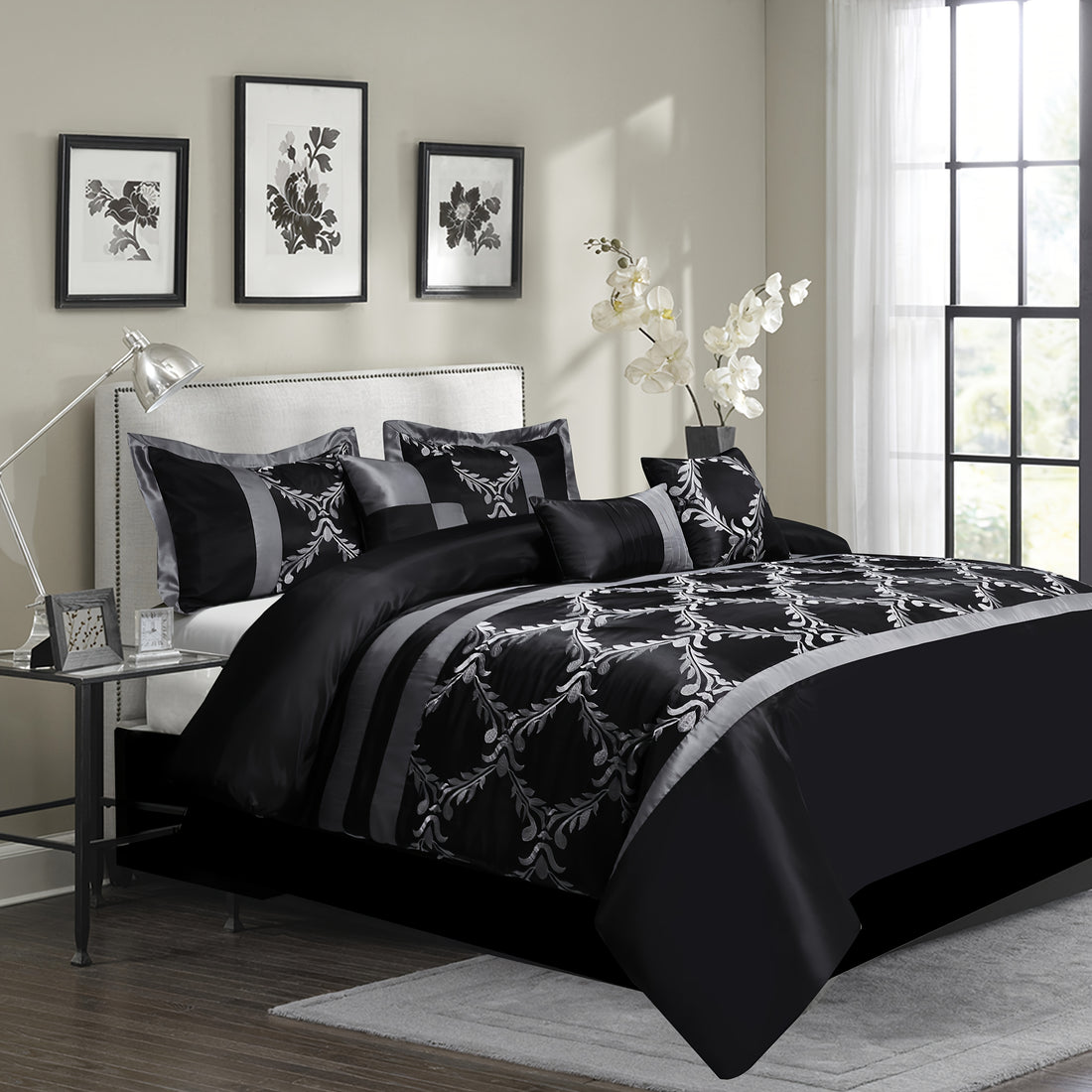Black and white floral comforter set on a bed in a bedroom with side table and decor.