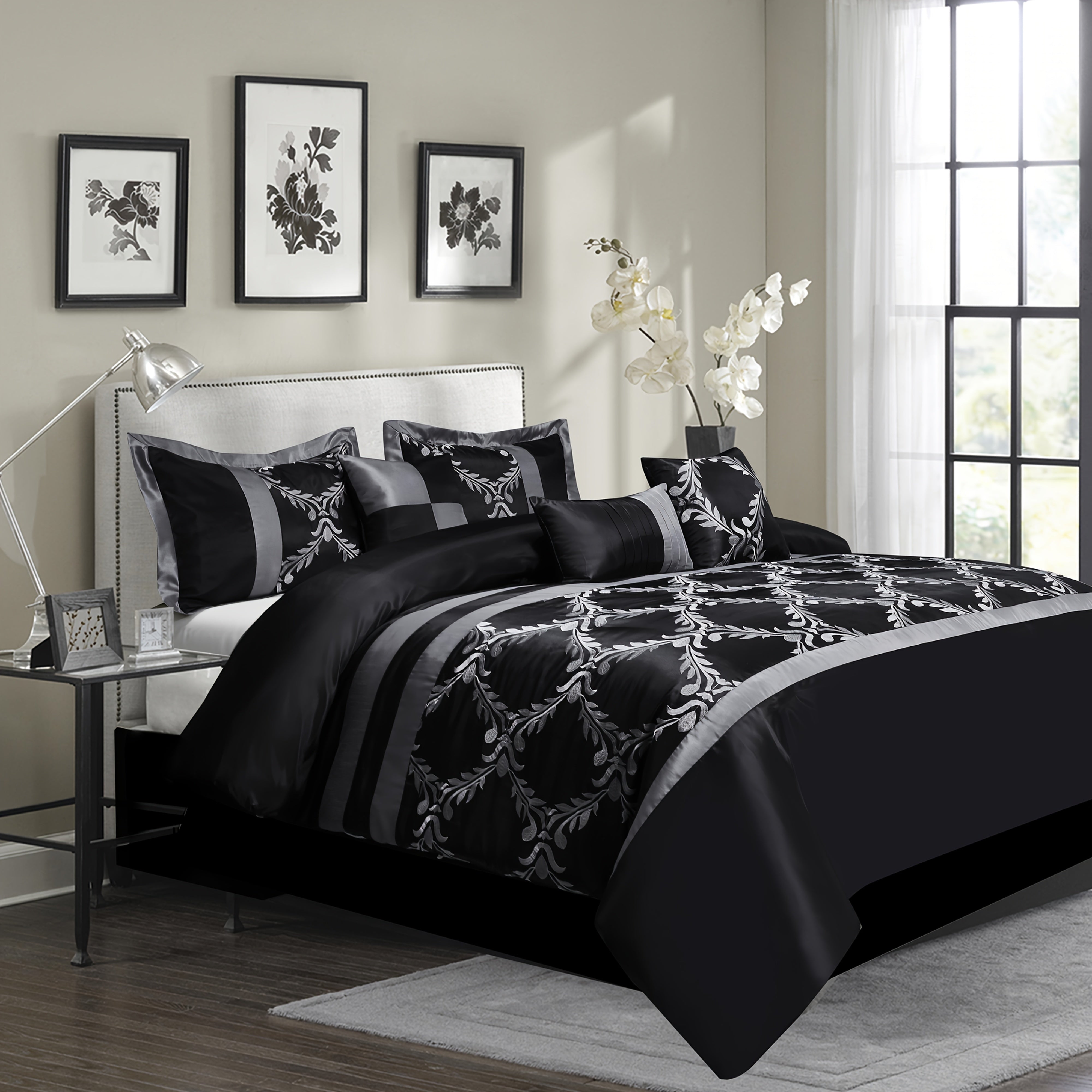 Black and white floral comforter set on a bed in a bedroom with side table and decor.