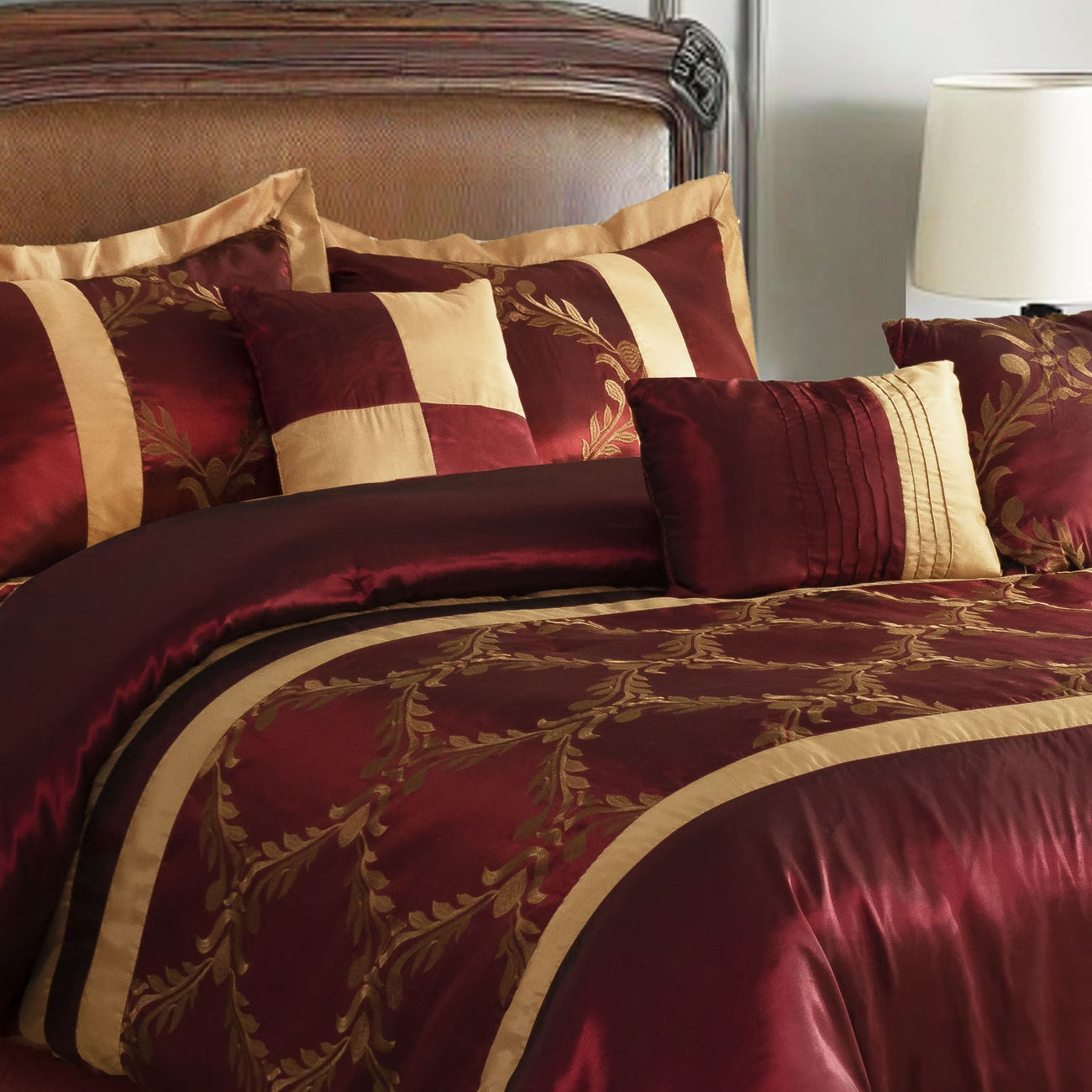 Maroon and gold bedding set on a bed with matching pillows.