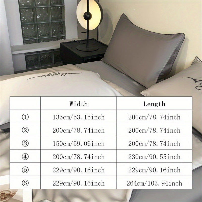 Bed with gray pillows and a duvet, featuring a table lamp and window in the background.
