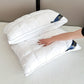 Two white pillows on a bed with a hand touching one of them, branded 'Royal.'