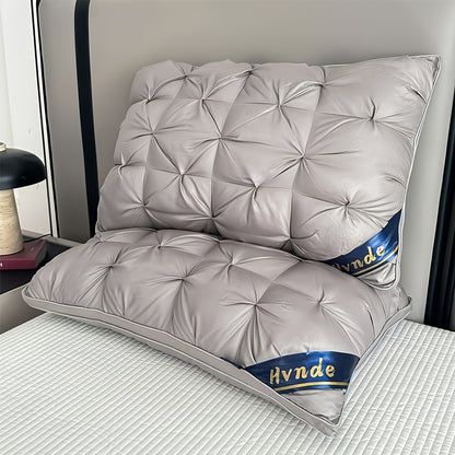 Gray quilted pillow with 'Hynde' branding on a bed