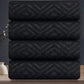 Stack of black towels with geometric pattern on a reflective surface
