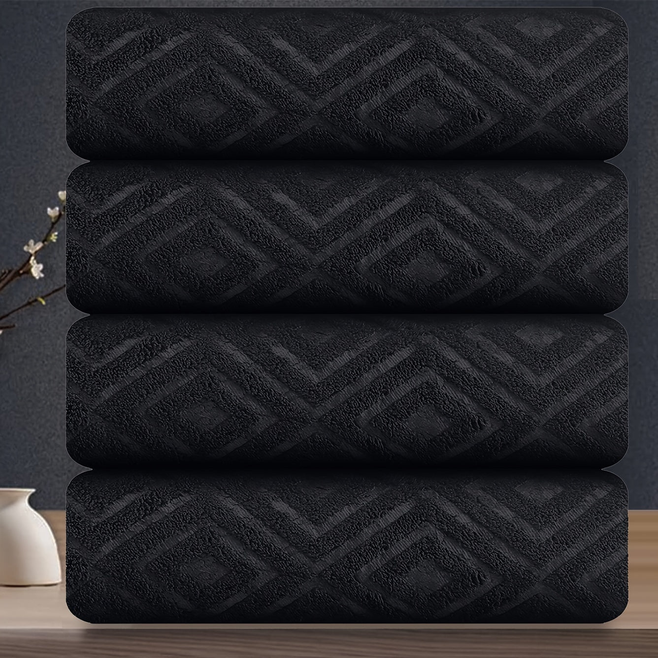 Stack of black towels with geometric pattern on a reflective surface
