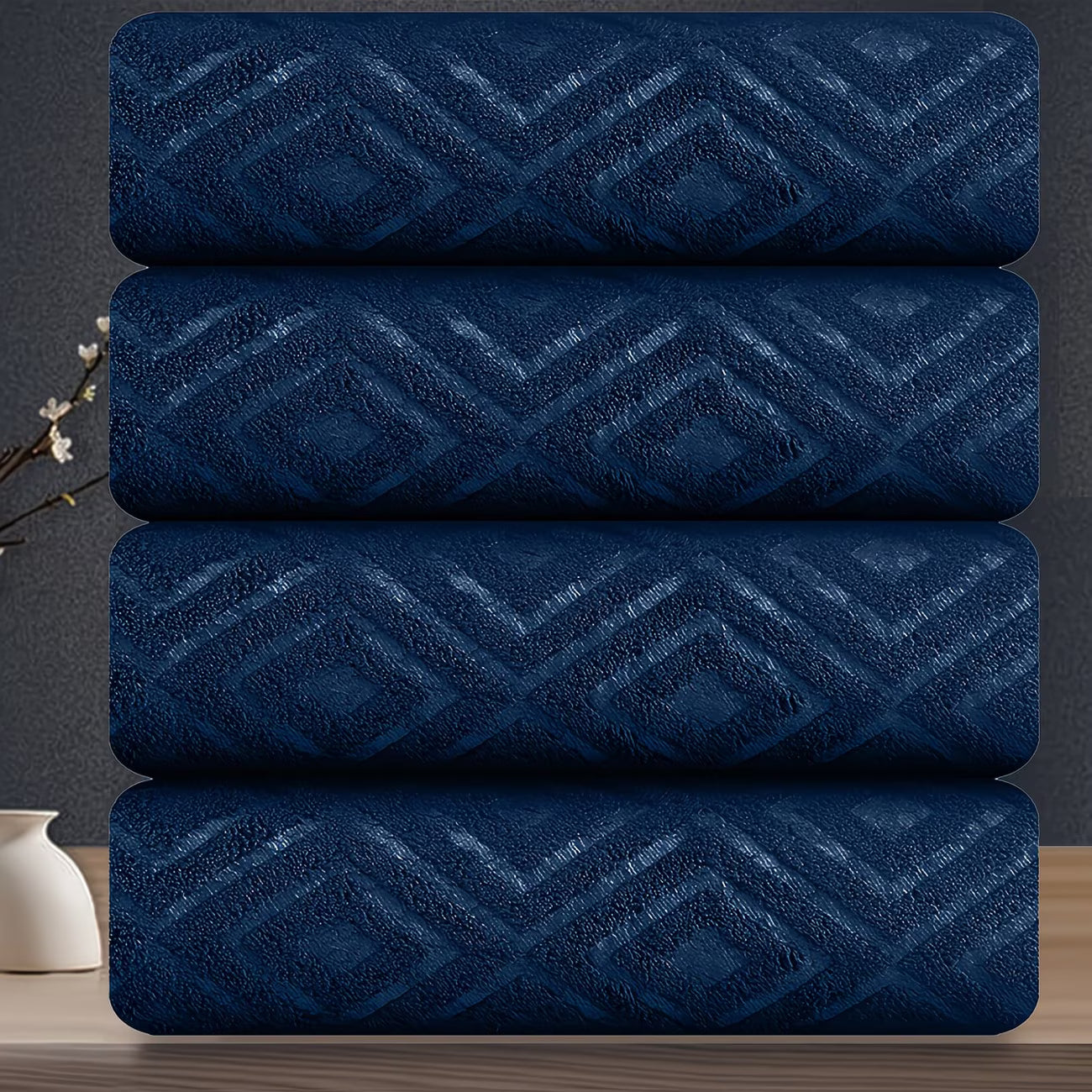 Stack of four blue towels with a geometric pattern on a dark background
