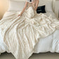 Person sitting on a bed with a fluffy white blanket, holding a book.