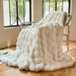 White fluffy blanket draped over a chair in a room with large windows.