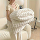 Person holding a large white blanket in a cozy living room.