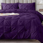 Purple textured comforter set on a bed with pillows and a lamp in the background.