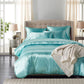 Turquoise bedding set on a bed in a well-lit bedroom with lamps and curtains.