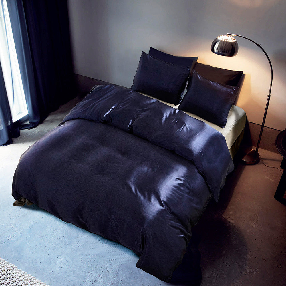Navy blue bedding set on a bed in a dimly lit bedroom with a lamp and curtains.