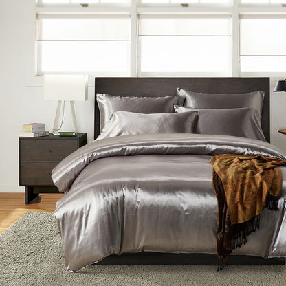 Gray satin bedding set on a bed with a wooden headboard and nightstand.