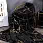 Black and gold marble patterned blanket draped over a chair in a room.