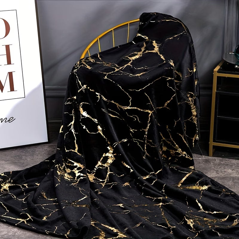 Black and gold marble patterned blanket draped over a chair in a room.