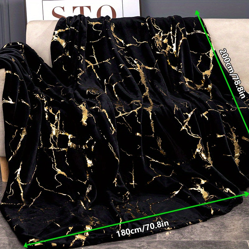 Black and gold patterned blanket on a sofa with measurement details.