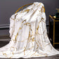 White fabric with gold marble pattern draped over a chair in a room setting.
