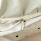 Close-up of a gold zipper pull on a beige fabric background