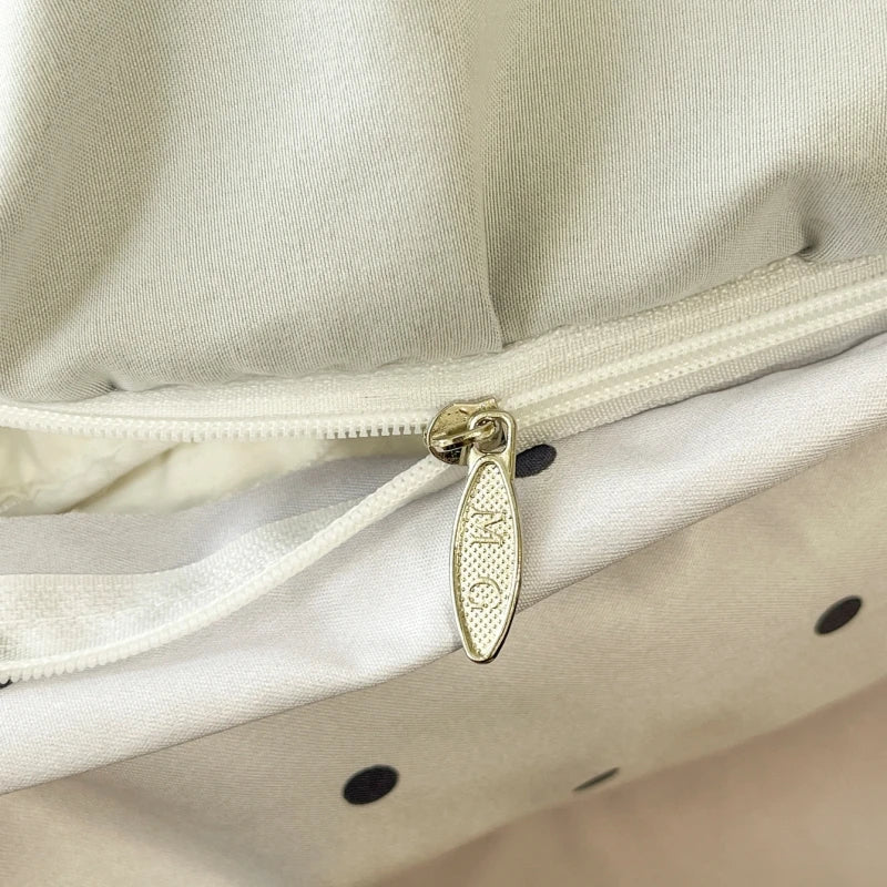 Close-up of a gold zipper pull on a beige fabric background