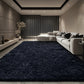 Modern living room with a large navy blue rug, gray sofa, and decorative elements.
