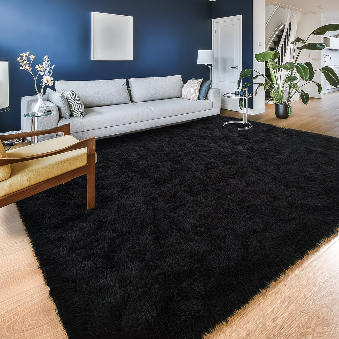 Living room with a black rug, gray sofa, and wooden floor.