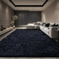 Modern living room with a dark blue rug, gray sofa, and decorative elements.