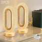 Two gold table lamps on a surface with a thermometer in the background.