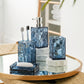 Bathroom accessories set with blue geometric design on a round mirror table.