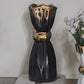 Black and gold decorative vase on a white surface with a blurred background
