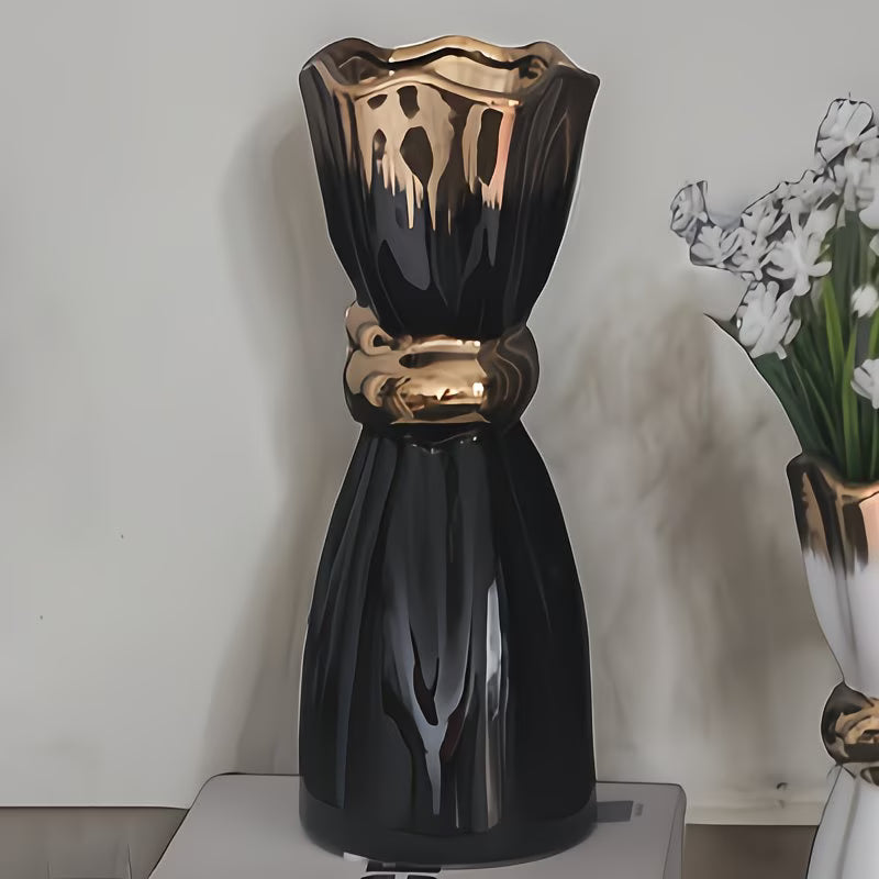 Black and gold decorative vase on a white surface with a blurred background