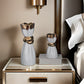 Decorative vases on a nightstand with a bed in the background