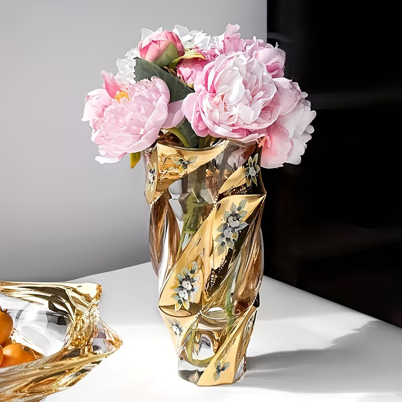 Gold decorative vase with pink flowers on a white surface