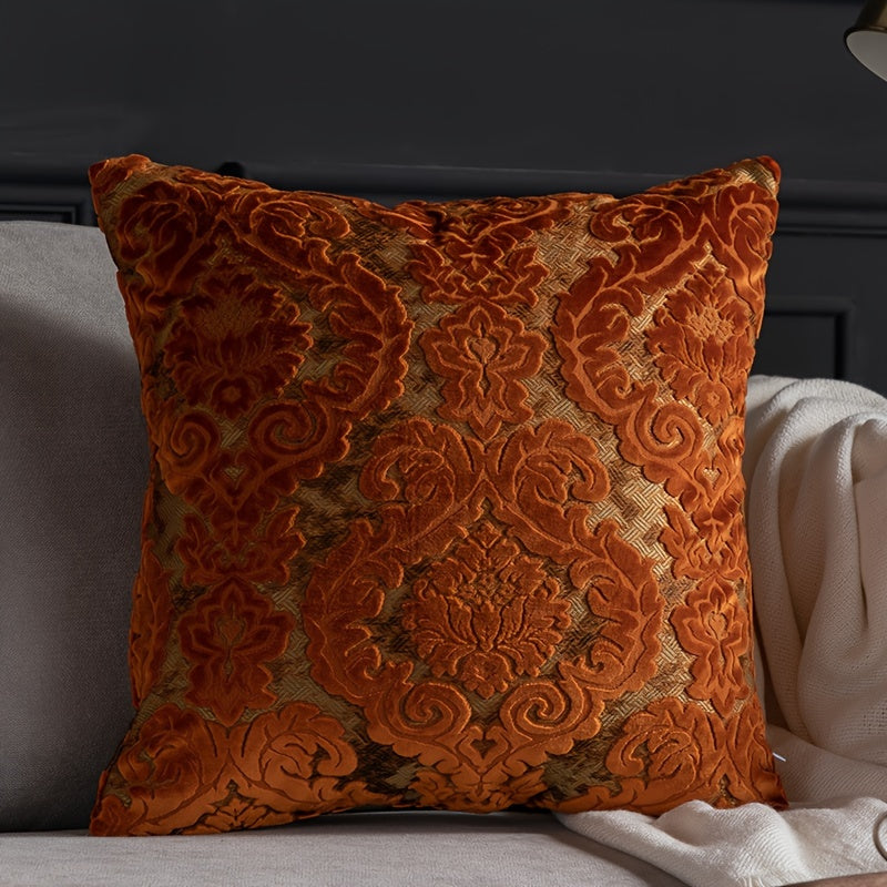 Decorative orange pillow with intricate patterns on a gray sofa.