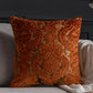 Decorative orange pillow with intricate patterns on a gray sofa.