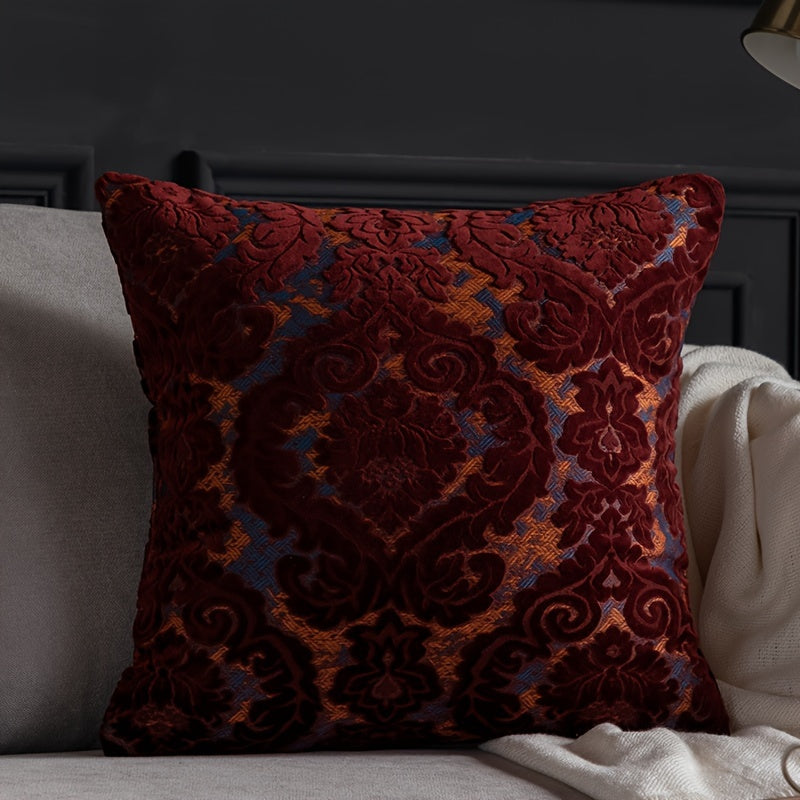 Decorative red pillow with intricate patterns on a gray sofa.