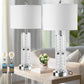 Two crystal table lamps with white lampshades on a wooden table in a living room setting.