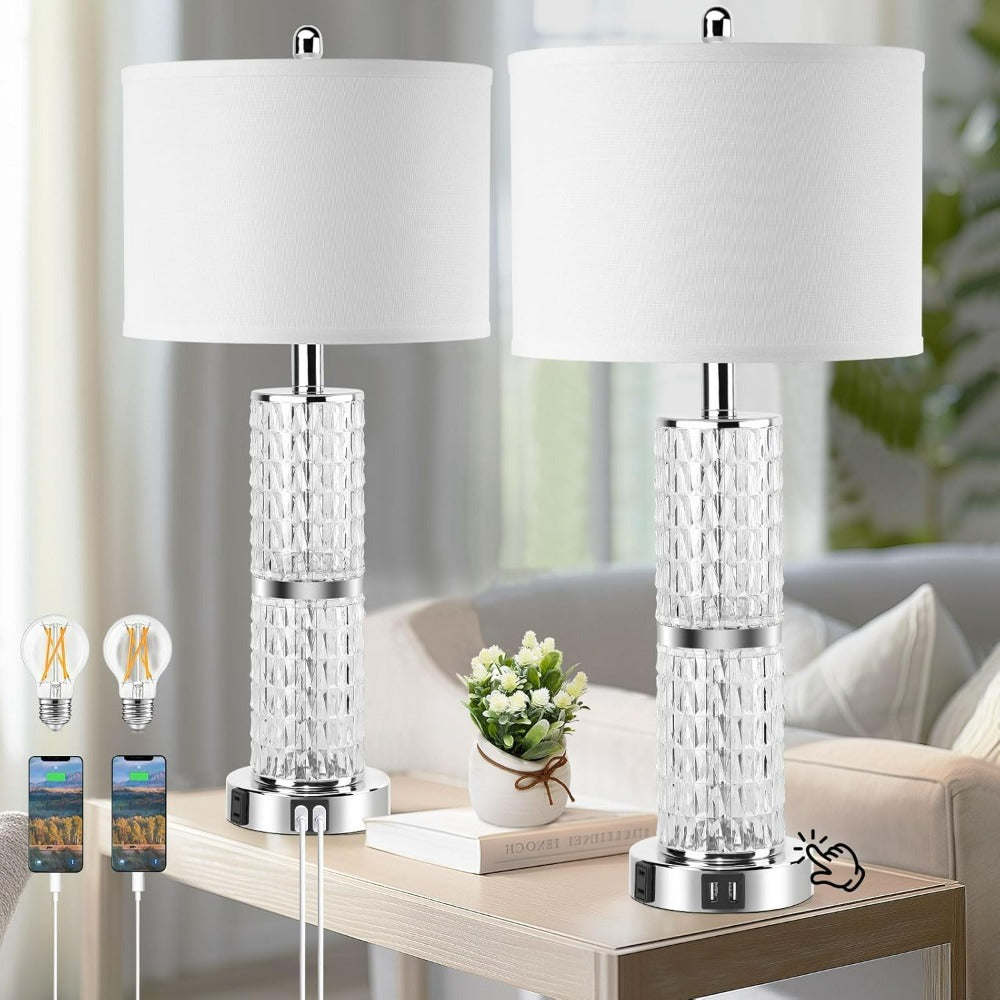 Two crystal table lamps with white lampshades on a wooden table in a living room setting.