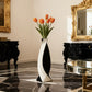 Decorative vase with orange tulips in a stylish room with black marble floor and gold-framed mirror.