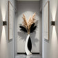 Modern interior with a vase of pampas grass and abstract art on gray walls.