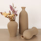 Three beige textured vases on a light brown surface with a plain background
