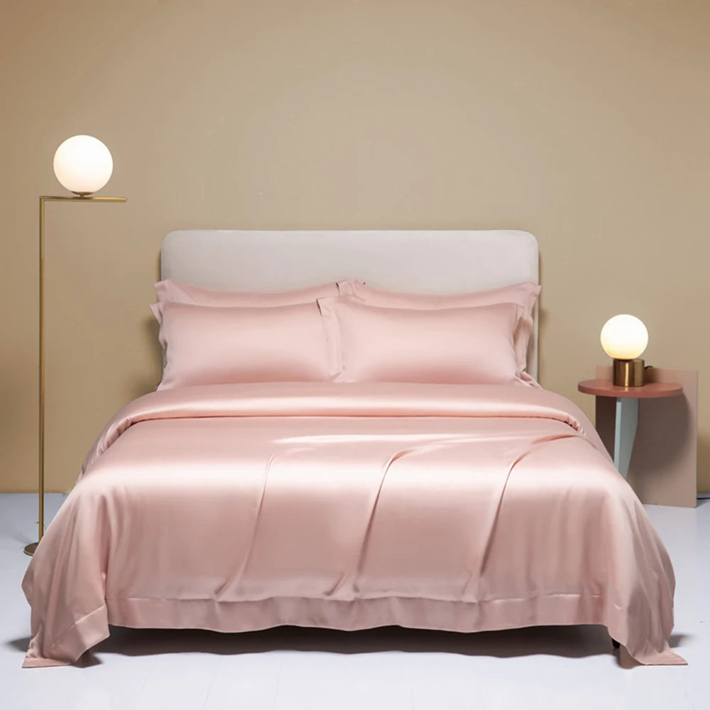 Pink satin bedding set on a bed with matching pillows in a minimalistic bedroom.