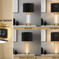 Table lamp with gold base and black shade, featuring a 2-button switch on a decorative shelf.
