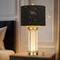 Decorative table lamp with black star-patterned shade on a wooden nightstand.