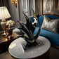 Decorative black and gold sculpture on a marble table in an elegant room.