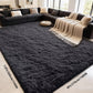 Large dark gray rug in a living room with a sectional sofa and decorative pillows.